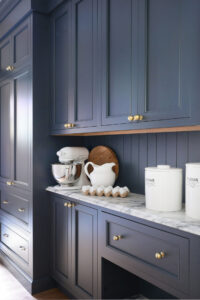 Butler's pantry with moody blue cabinetry, brass knobs, marble countertops