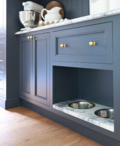 Butler's pantry with moody blue cabinetry, brass knobs, marble countertops, built-in dogs bowls with marble
